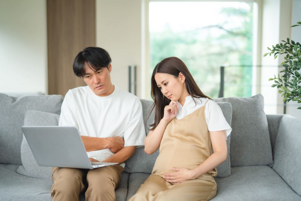 パソコンをみながら悩む妊婦と男性