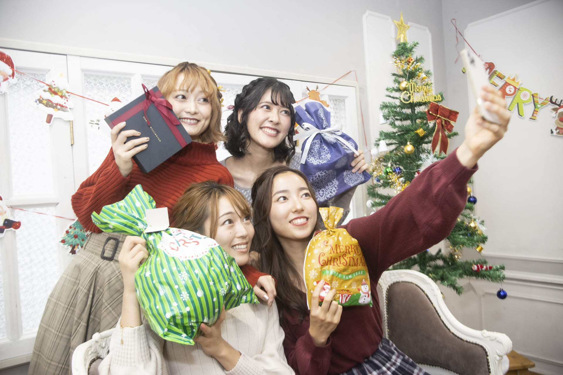 クリスマスプレゼントを持って自撮りする女性たち