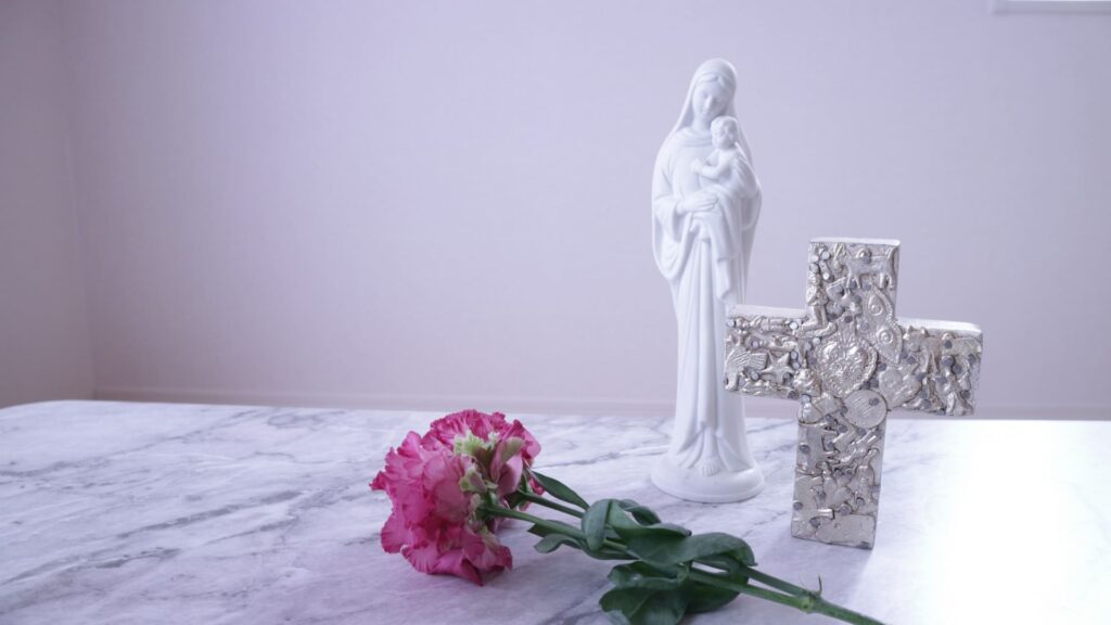 マリア像と十字架のモチーフと花