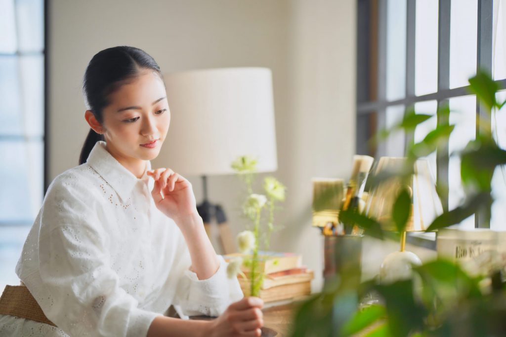 白い花をもって考える女性