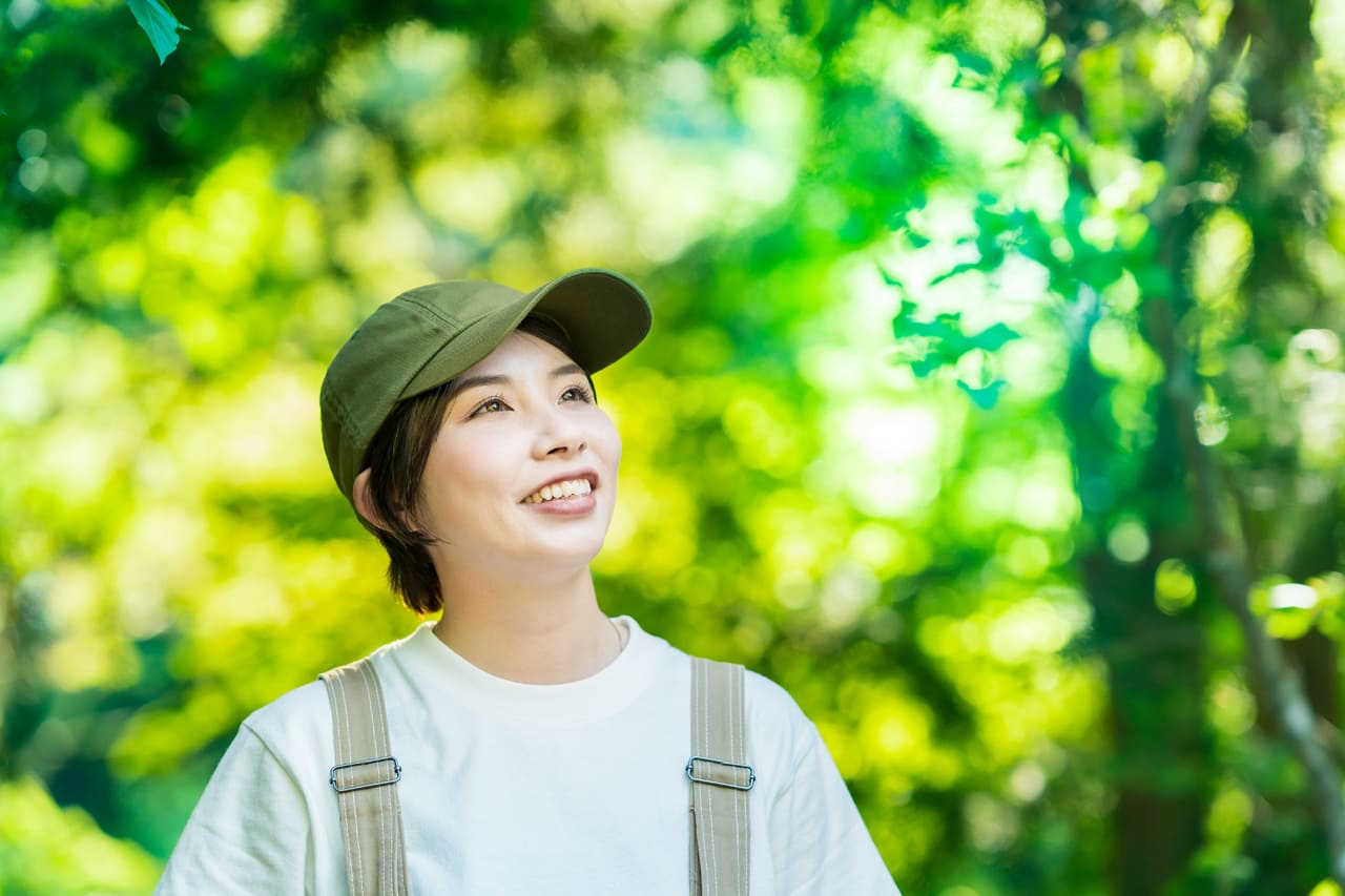 森の木々を見上げる女性