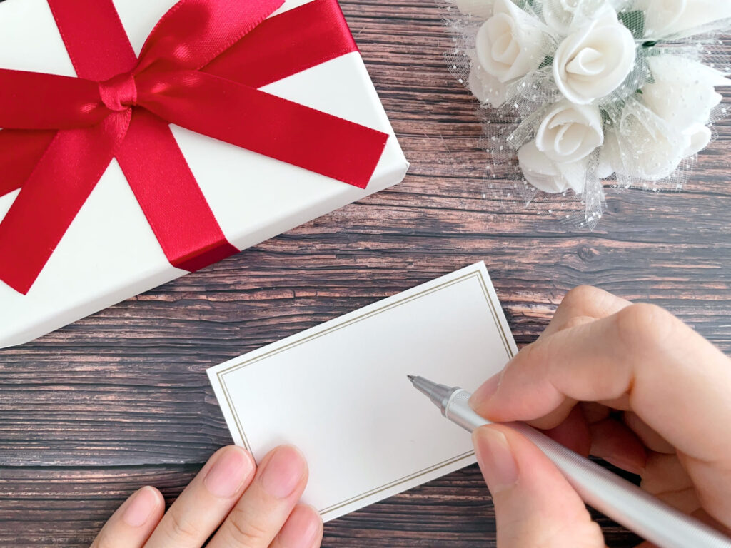 プレゼントとメッセージカードを書く手元