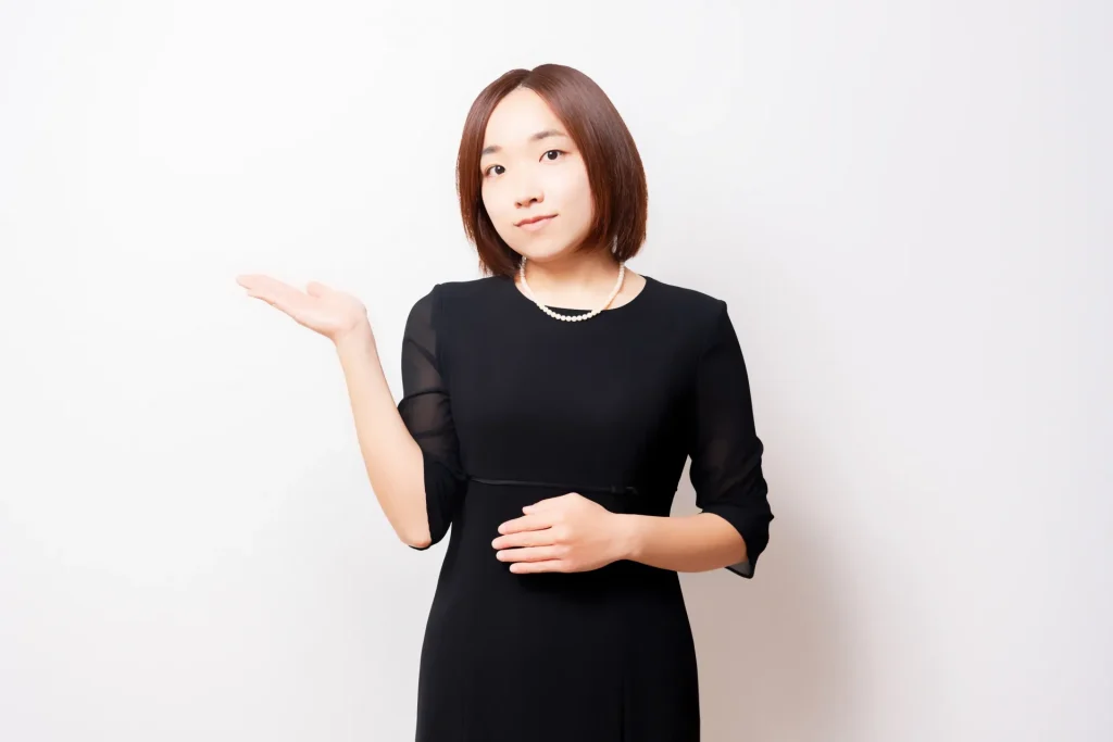 案内のポーズをしている喪服を着ている女性