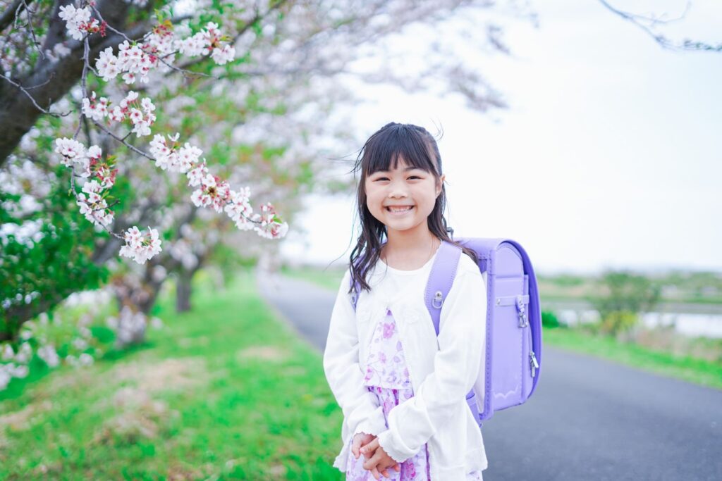 桜が咲く中登校する小さな女の子