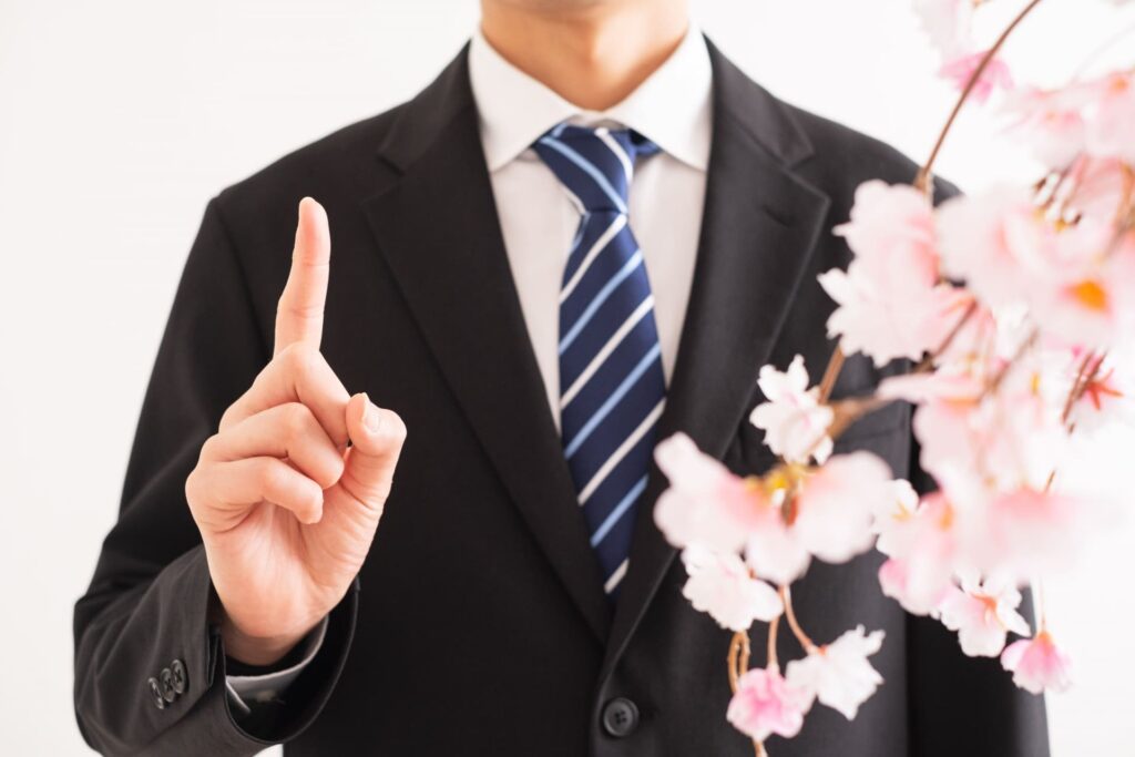 人差し指を立てるスーツの男性と桜